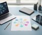 Laptop and tablet on a desk with blank paper showing a color concept web made of connected circles and lines beside a pencil and sticky notes